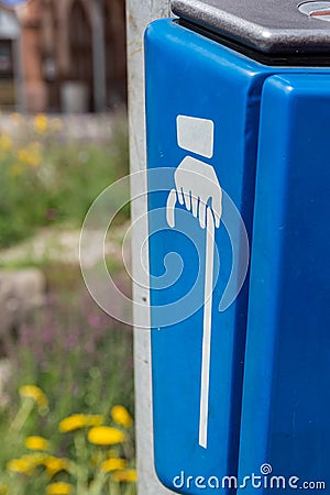 Blue bin outdoors in a street with hand with cane Stock Photo