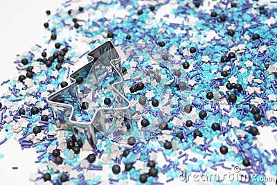 Blue star shaped sugar sprinkles with metal christmas tree biscuit cutter in advent season Stock Photo