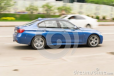 Blue BMW 320d sedan F30 car moving on the street. Side view of BMW 3 Series auto driving on the road with urban blurred background Editorial Stock Photo