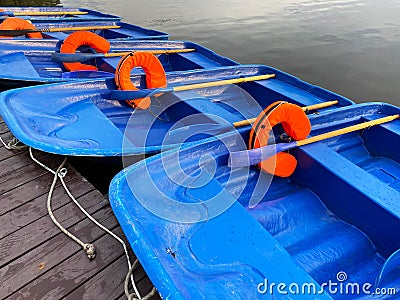 Blue boats with oars and orange lifebuoys Stock Photo