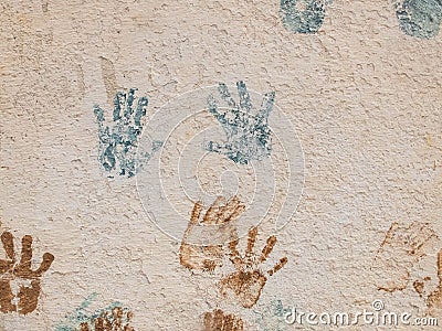 Blue and brown paint palm prints on the textured plaster Stock Photo