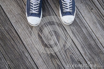 Blue Canvas Sneakers on Feet on Wood Stock Photo