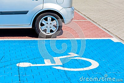 Blue car parking spot for the disabled, handicapped. Wheelchair symbol painted on the ground, parking lot vehicle space, closeup Stock Photo