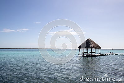 blue Caribbean sea with crystal clear waters and clear sky. a bungalow with a pier in the middle of the lagoon in a coral Stock Photo