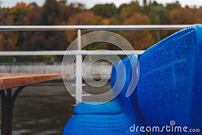 Blue chairs in raindrops on a pleasure boat in Moscow, autumn park in the background Stock Photo