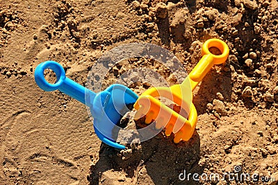 Blue childrens spatula and yellow rake, stuck in sand Stock Photo