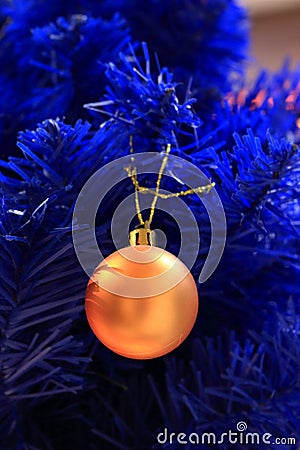 Blue christmas tree with yellow bulb. Blue artificial pine tree branch with golden ball. Festive happy new year decoration. Stock Photo