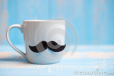 Blue coffee cup with Black mustache on wood table background in the morning. Father, International men day, Prostate Cancer Stock Photo