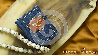 Hindu holy book and cowrie shell on a wooden surface with golden satin cloth Stock Photo