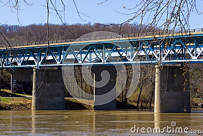 A Blue Concrete and Steel Bridge over a Brown River Stock Photo
