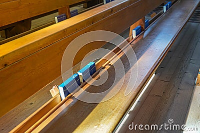 Blue cover Catholic prayer books on church chairs, German language Stock Photo