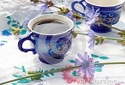 Blue cup of coffee tea chicory drink with chicory flower, hot beverage on embroidered fabric background Stock Photo