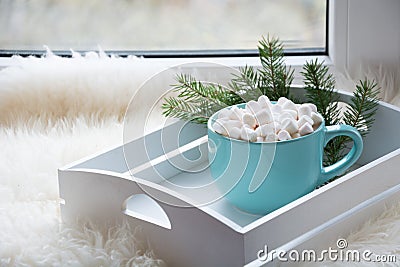 Blue cup of hot chocolate with marshmallow on windowsill. Weekend concept. Home style. Christmas time. Stock Photo
