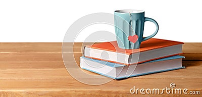 Blue cup with red heart on green and orange books Stock Photo