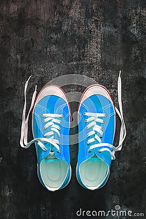blue-cyan-green-turquoise sneakers with untied laces on a dark concrete background. Copy space. View from above Stock Photo