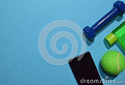 Blue dumbbell, sneakers and bottle indicating workout plan on blue background. Stock Photo