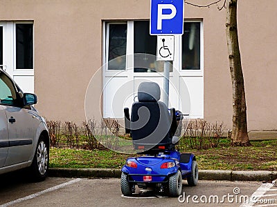 Blue electric disability or handicap scooter in handicap parking stall. Stock Photo