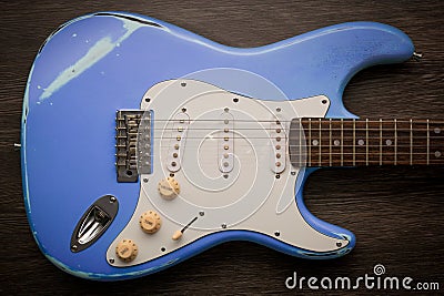 Blue electric guitar against brown wood background. Vintage age worn guitar Stock Photo