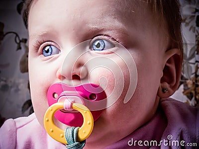 Blue-eyed Baby sucking pacifier Stock Photo