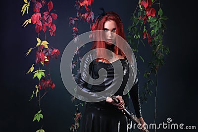 Blue Eyed Red Head Gothic Girl Pulling out a fantasy sword among autumn vines Stock Photo