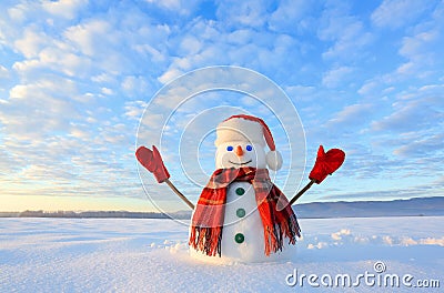Blue eyed snowman. Sunrise enlightens the sky and clouds by warm colors. Reflecting on the snow. Mountains landscape. Joyful cold Stock Photo