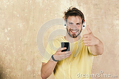 Blue eyed stylish hipster with smartphone. American handsome bearded guy with headphones. European man have fun time Stock Photo