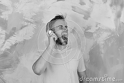 Blue eyed stylish hipster with smartphone. American handsome bearded guy with headphones. Musical lifestyle. Cheerful Stock Photo