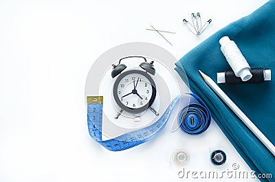 Blue fabric, watch, sewing tools and needlework accessories: threads, pins, bobbins, buttons, needles, measuring tape on a white Stock Photo