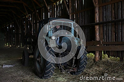 Blue farm tractor with tractor driver, under roof of hayloft. Editorial Stock Photo