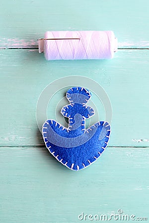 Blue felt anchor ornament and white thread on wooden background. Embroidery crafts for kid. Step. Closeup. Top view Stock Photo