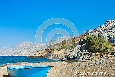 Blue fishermans boat and evergreen tamarisks on Alexi or Alexis beach near Emborios Greek village on Kalymnos island Stock Photo