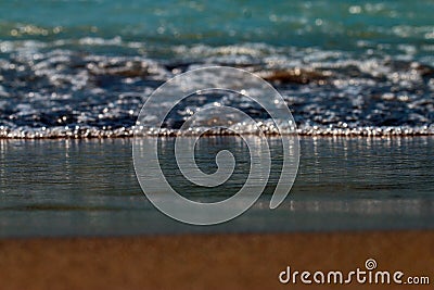 Blue foamy waves coming to brown sandy beach. Stock Photo