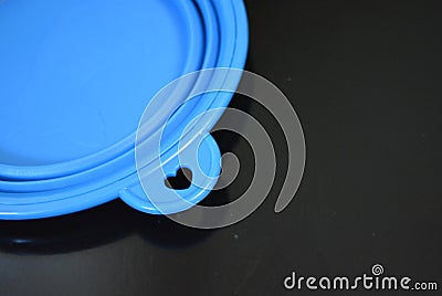 Blue folding and multifunctional rubber plate, a bowl with a plastic edging on a black glossy surface. Stock Photo