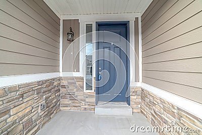 Blue front door of a home with sidelight and outdoor wall lamp at the entrance Stock Photo