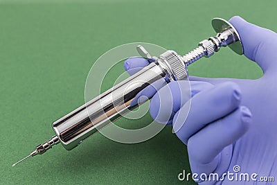 Blue-gloved hand holds a syringe Stock Photo