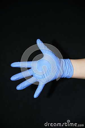 Blue gloved hand outstretched open palm side, on black background Stock Photo