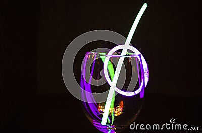 Blue and green glow stick on a wine glass and colourful light reflection aginst the dark background party photography Stock Photo