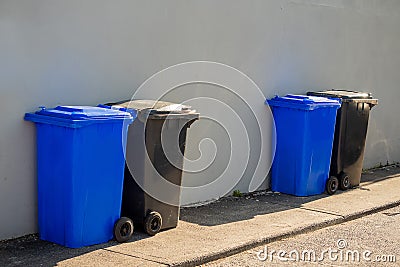 Blue and grey plastic wheelie bins out in a street ready for collection. Recycle industry concept. Disposal of household waste Stock Photo