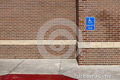 Blue handicapped parking sign on a red brick wall of an office building in the United Sates of America Stock Photo