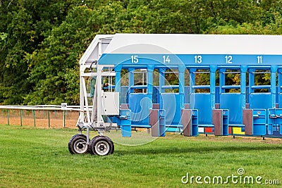 Blue horse racing starting gate on start by tractor machine at equiestrian racehorse hippodrome. Outdoor sport Stock Photo