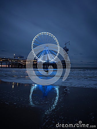 Blue hour panorama of surfer on beach with illuminated sky view ferris wheel pier of Scheveningen The Hague Netherlands Editorial Stock Photo