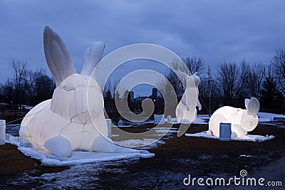 Blue hour view of three glowing giant inflatable rabbits from the artist Amanda Parerâ€™s Intrude Family Editorial Stock Photo