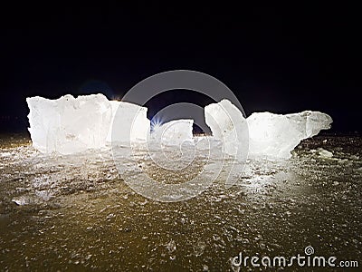 Blue ice cubes shine on flat glacier surface. Thanks to spot light shine details Stock Photo