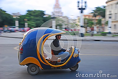 Blue iconic Coco auto rickshaw taxi fast speeding on blurred background of yank tank tanks, Capitol National at Havana, Cuba Editorial Stock Photo