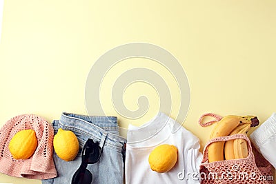 Blue jeans, white shirt, sunglasses, string bag and crochet hat and lemons on yellow background. Women`s stylish spring summer Stock Photo