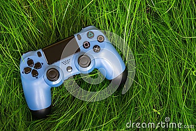 A blue joystick from a game console on green grass Editorial Stock Photo