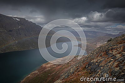 Blue lake with rainbow in mountain landscape from above the hike to Knutshoe summit in Jotunheimen National Park in Norway Stock Photo