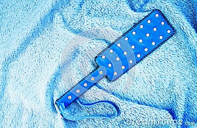 Blue leather slap on bed. Accessories for adult sexual games. Toys for BDSM, spanking devices. Spanking and punishment concept. Stock Photo