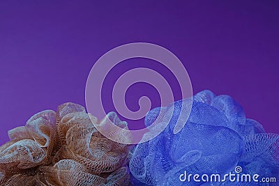 Blue and light brown mesh bath sponge on a violet background. Text space. Hygiene, decoration, background concept. Minimal style Stock Photo