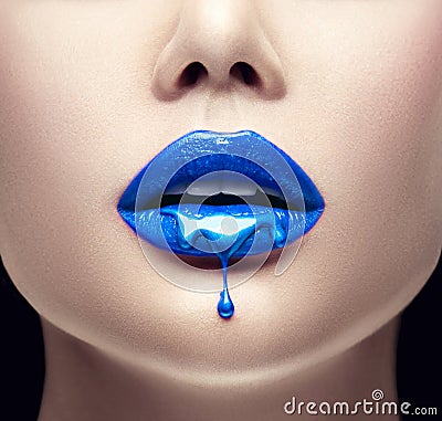 Blue lipstick dripping. Lipgloss dripping from lips, Blue liquid drops on beautiful model girl`s mouth, creative makeup Stock Photo